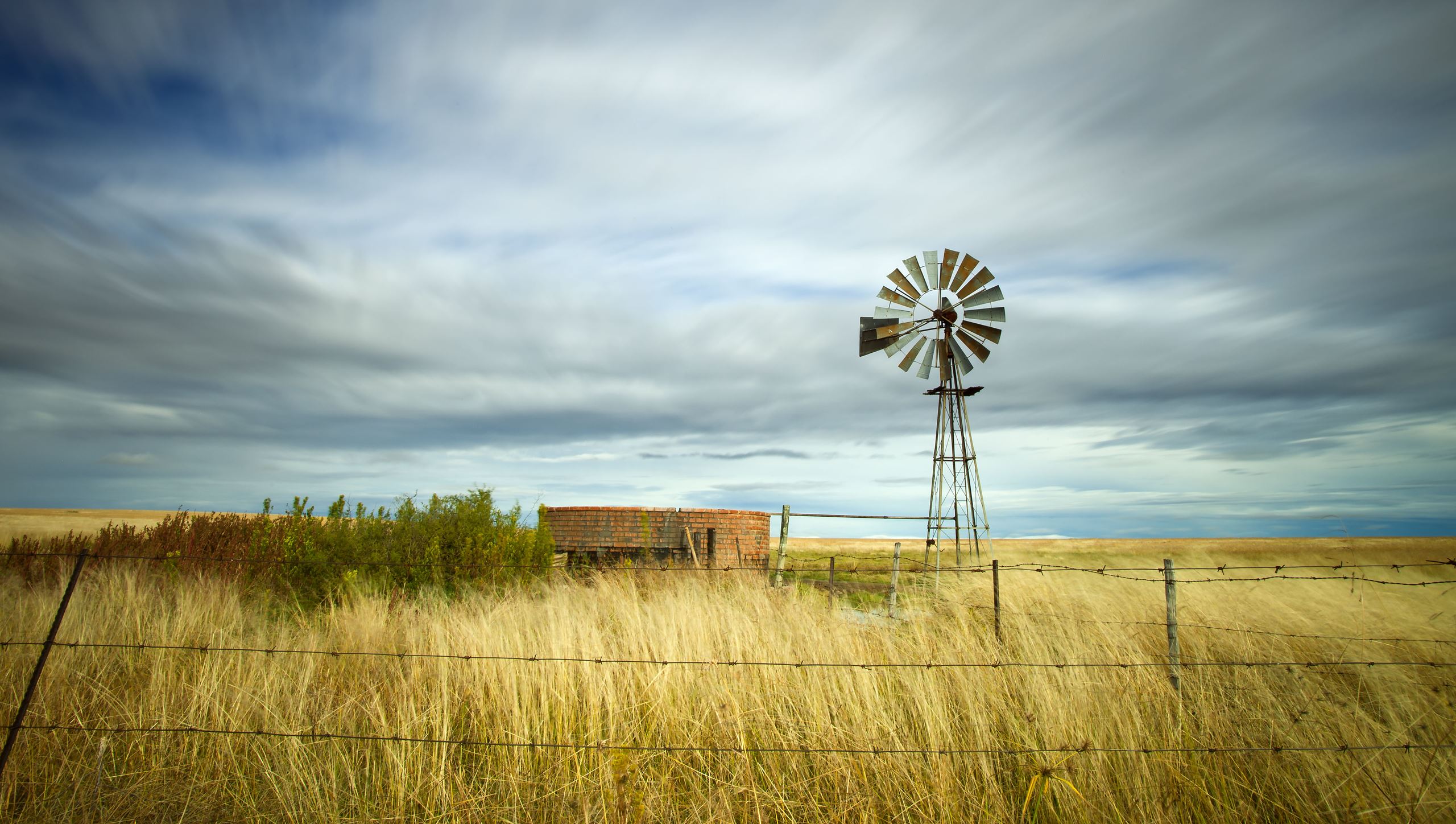 windmill and small brick building in a field