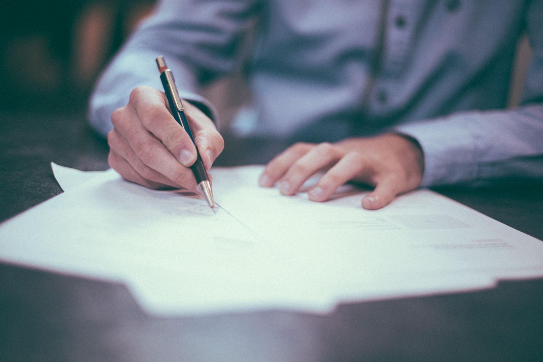 person writing on papers with a pen