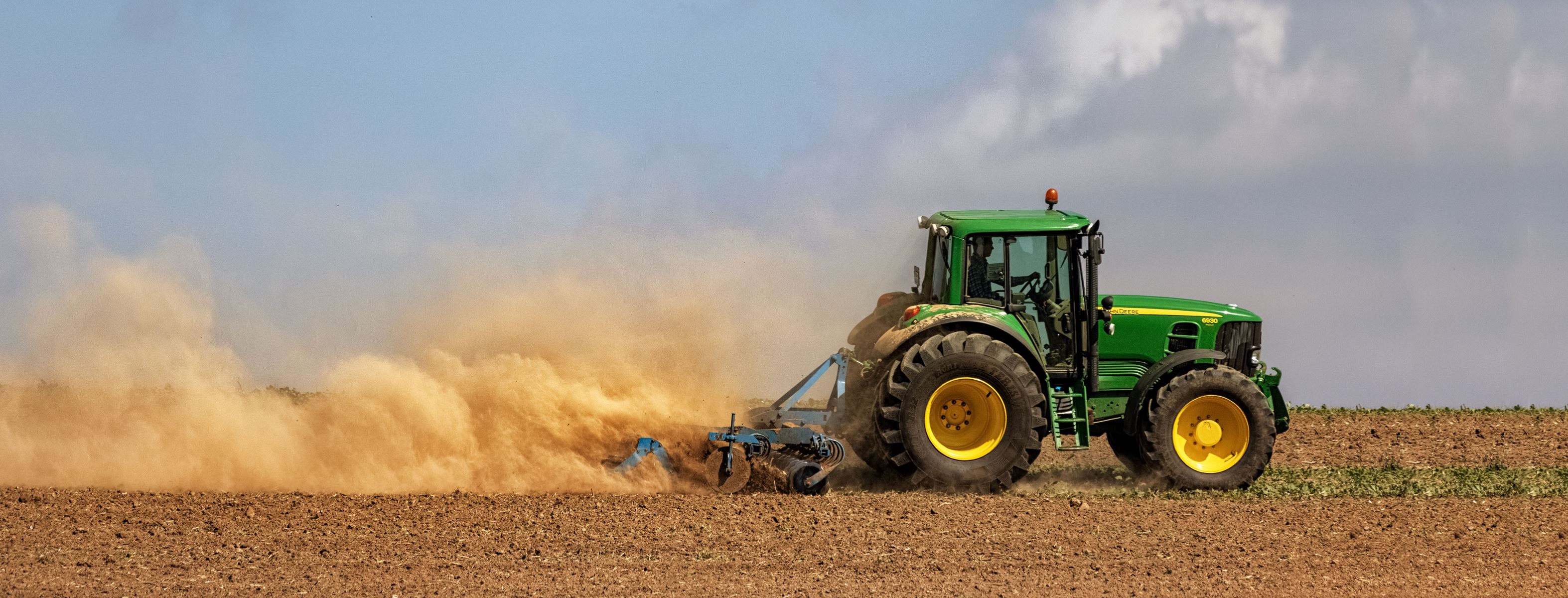 tractor pulling discs in dry dirt field